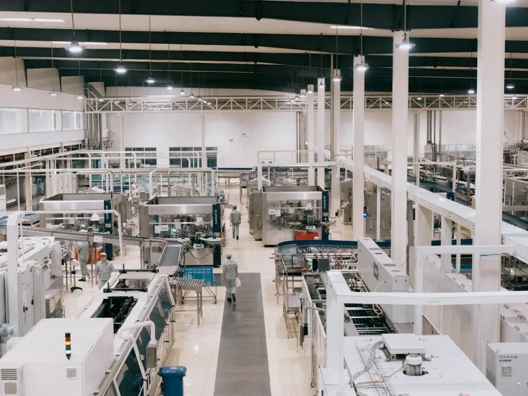 Operators on a plant packaging line among filling machines, conveyors, and stainless equipment.